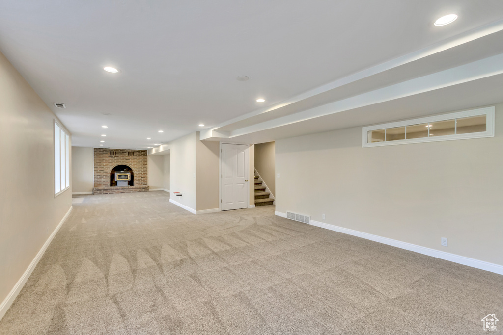Finished basement with light carpet, stairway, recessed lighting, and a fireplace