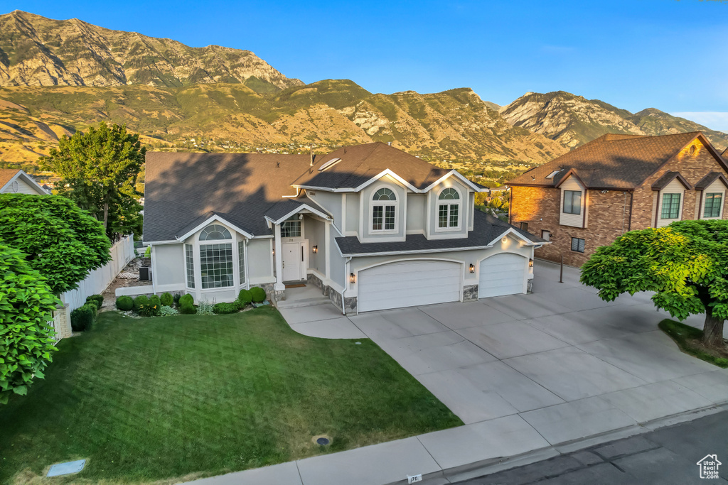 View of front of property featuring driveway, an attached garage, a mountain view, and stucco siding