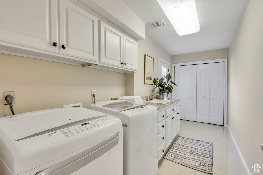 Laundry room featuring separate washer and dryer, cabinet space, and light tile patterned flooring