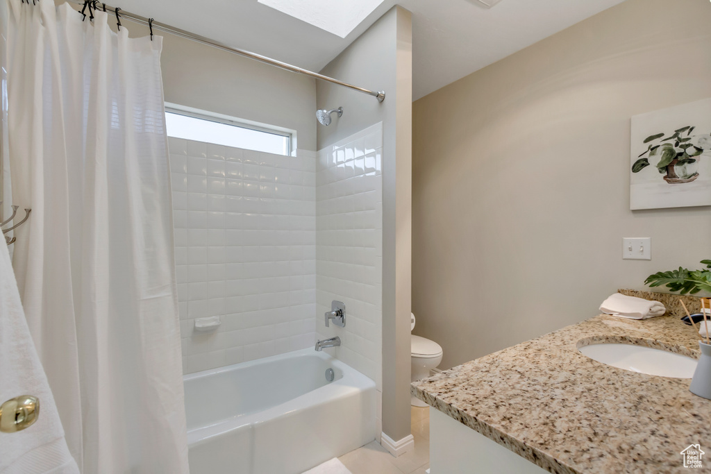Full bath with vanity, shower / bathtub combination with curtain, tile patterned floors, and a skylight