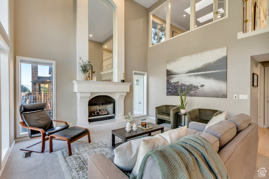 Living area featuring a towering ceiling, a fireplace with raised hearth, and recessed lighting