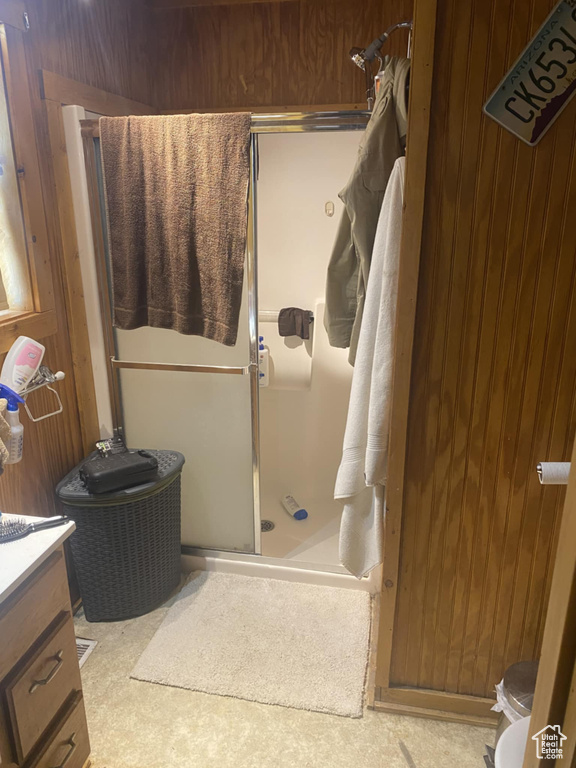 Full bath featuring a shower stall, vanity, and wood walls