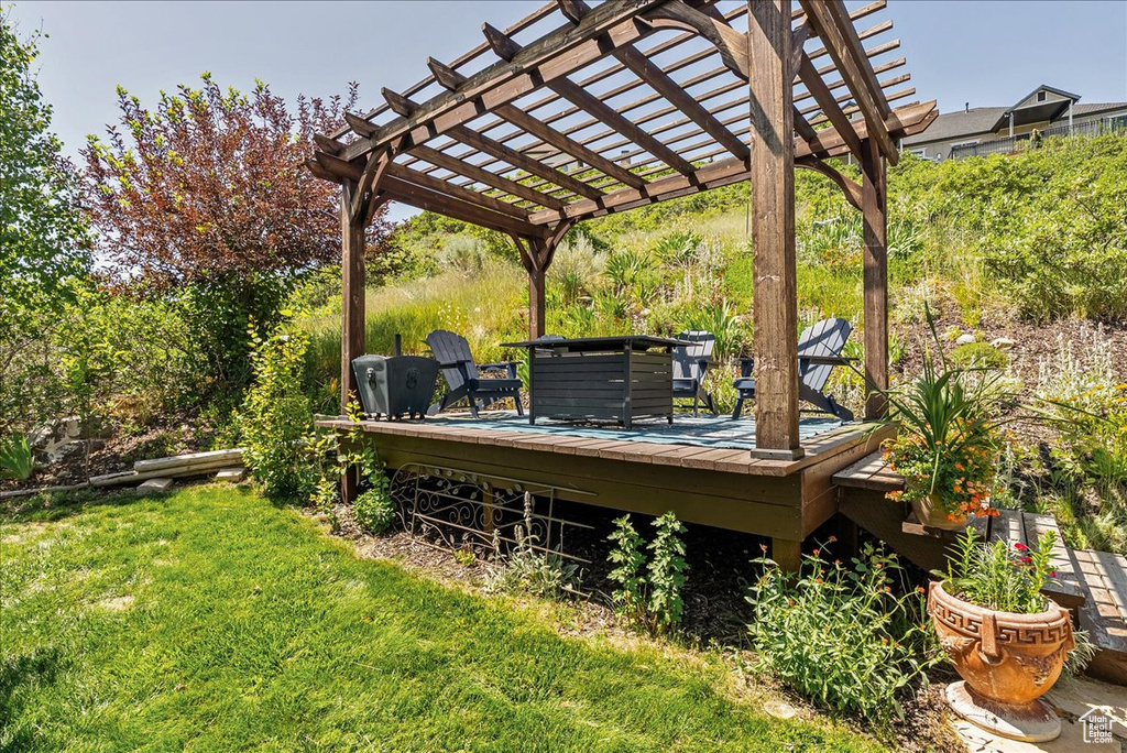 View of grassy yard with a wooden deck and a pergola