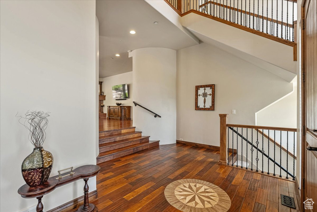 Stairway with hardwood / wood-style floors, recessed lighting, and a high ceiling