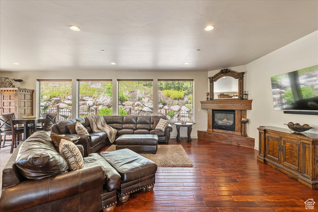 Living area with healthy amount of natural light, a glass covered fireplace, dark wood-type flooring, and recessed lighting