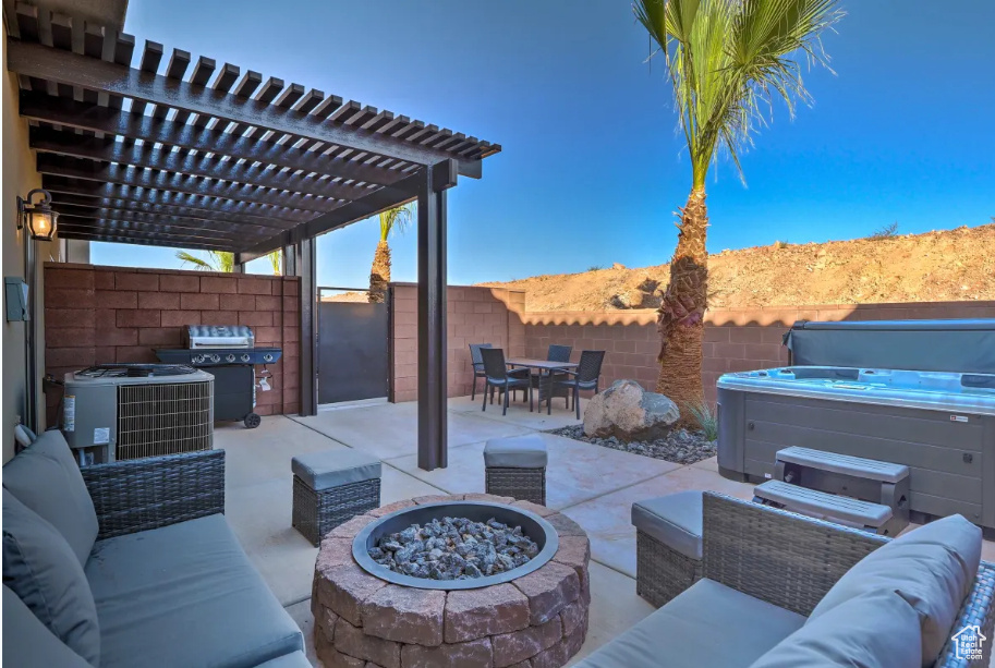 Fenced backyard featuring a hot tub, a patio, area for grilling, an outdoor living space with a fire pit, and a pergola