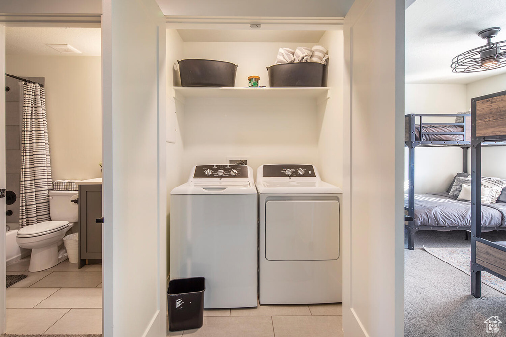 Laundry room with washing machine and dryer and light tile patterned floors