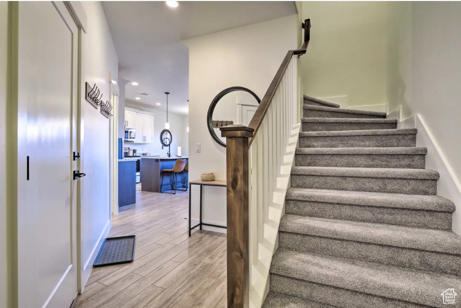 Staircase featuring wood finished floors and recessed lighting