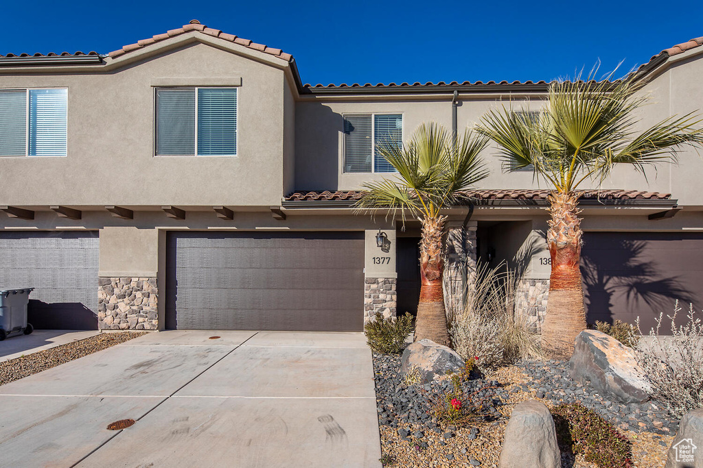 View of front of house featuring concrete driveway, stucco siding, stone siding, and a garage