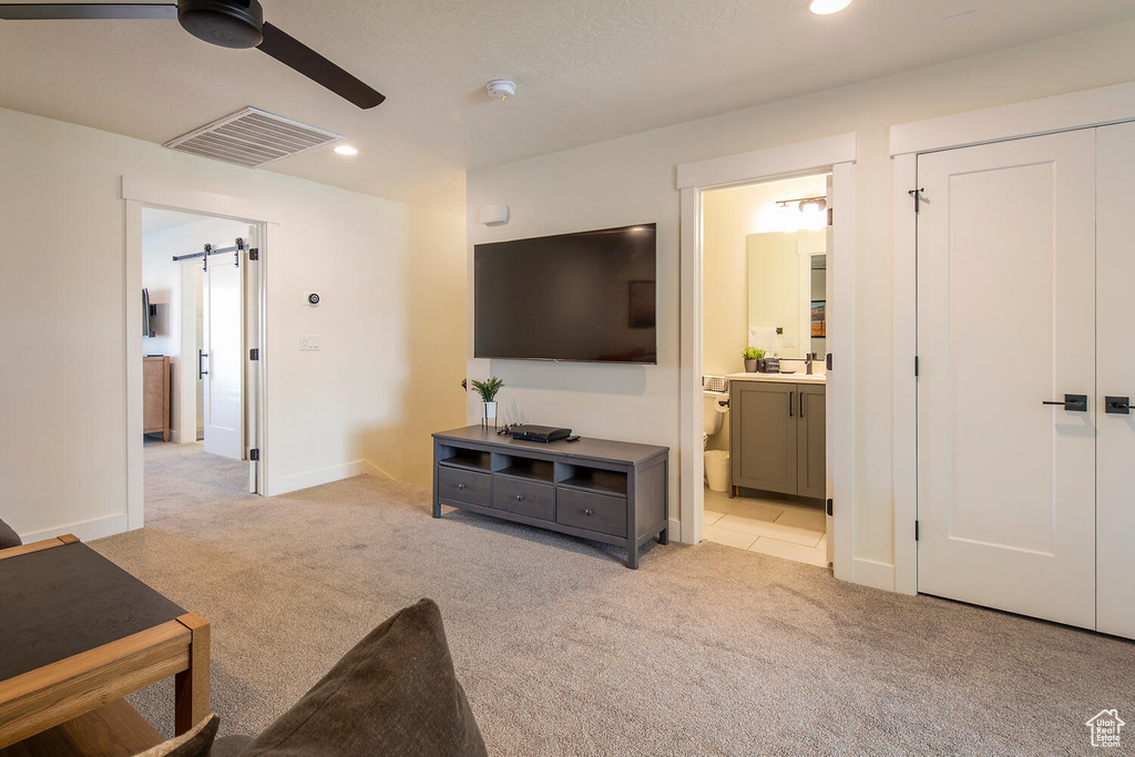 Living area featuring light carpet, ceiling fan, recessed lighting, and a barn door