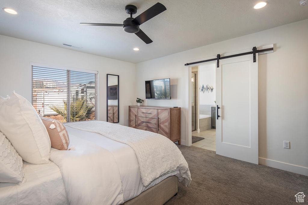 Bedroom with a barn door, recessed lighting, light carpet, ceiling fan, and ensuite bathroom