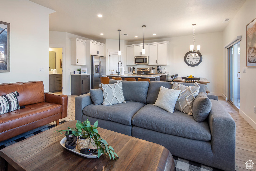 Living area with light wood-type flooring, recessed lighting, and a chandelier