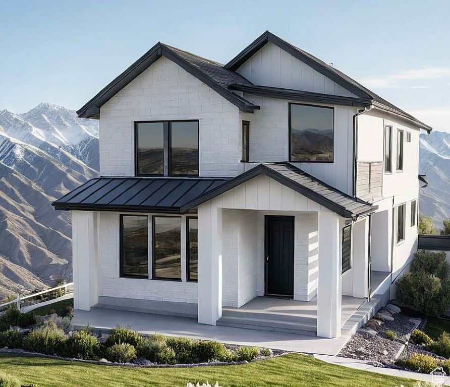 View of front of house featuring a standing seam roof, a mountain view, covered porch, and a metal roof