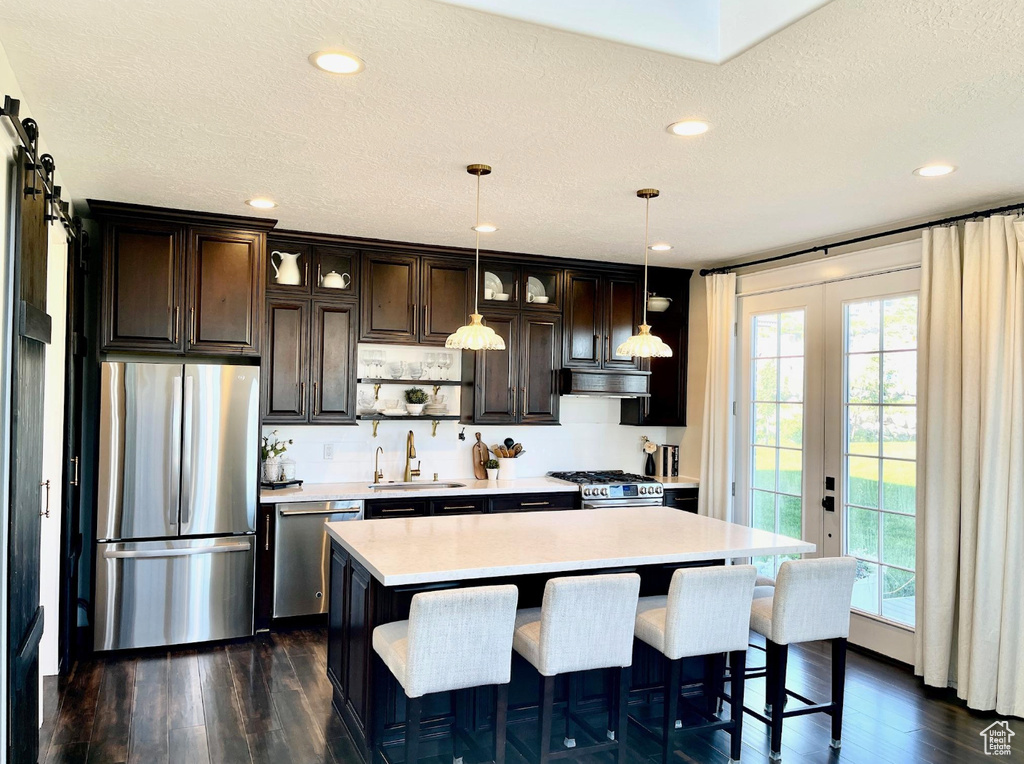 Kitchen featuring appliances with stainless steel finishes, light countertops, dark wood-style floors, recessed lighting, and a textured ceiling