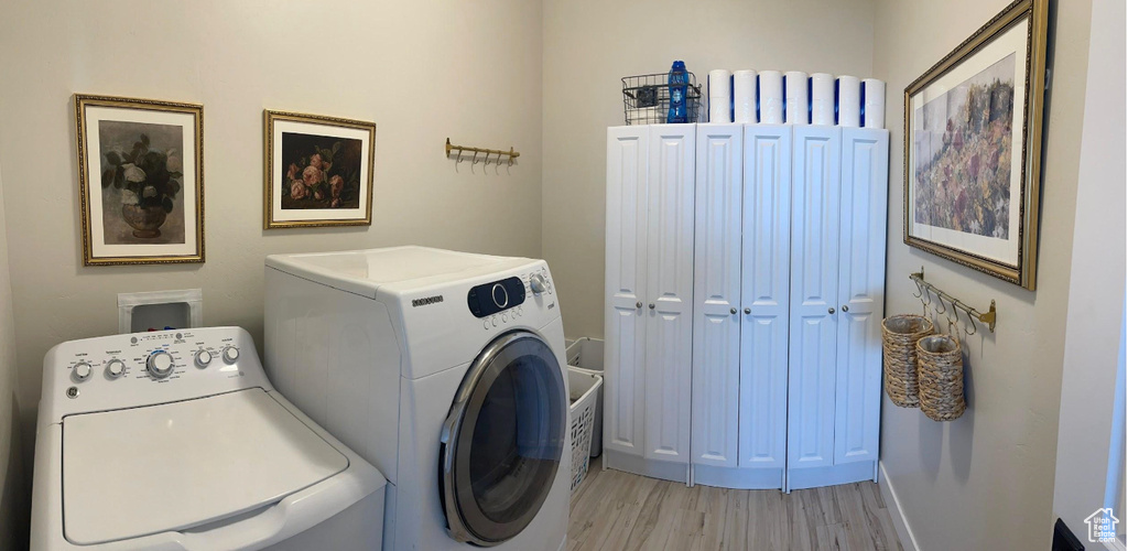Laundry area featuring washing machine and clothes dryer and light wood-type flooring