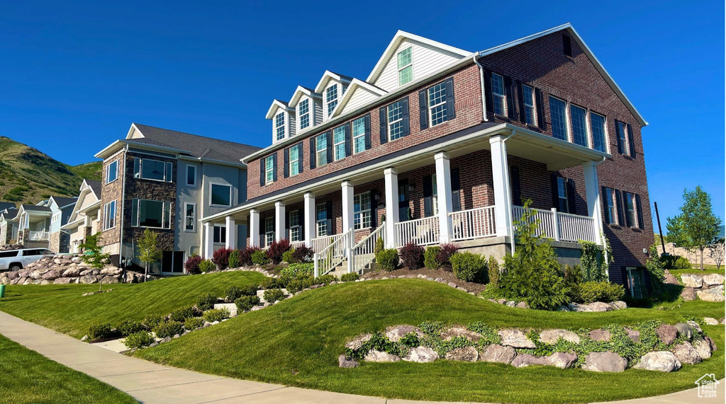 Colonial house with covered porch, brick siding, and a front yard
