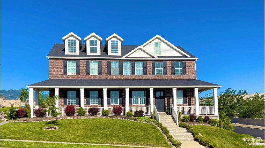 View of front facade featuring a porch, brick siding, and a front lawn
