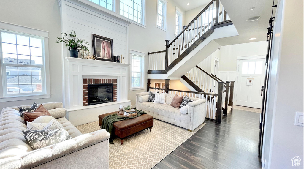 Living room featuring stairs, dark wood-style floors, a high ceiling, and a fireplace