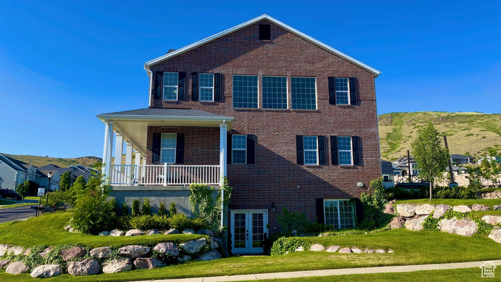 View of front facade with french doors, a front lawn, brick siding, and a mountain view