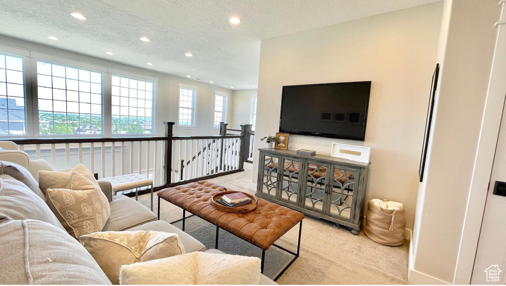 Carpeted living area with recessed lighting and a textured ceiling