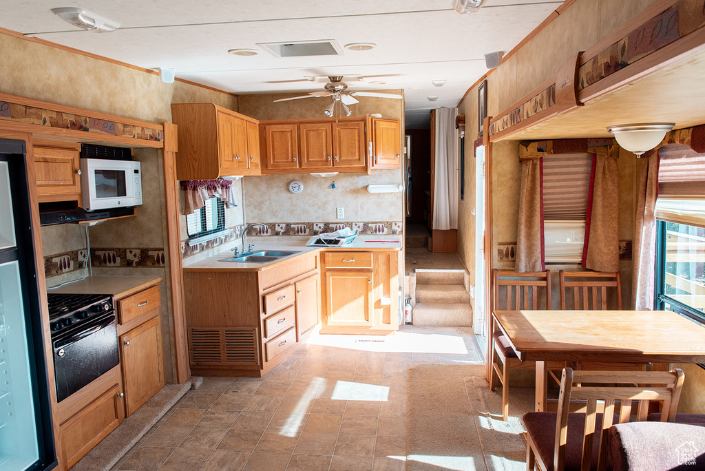 Kitchen featuring white microwave, oven, a ceiling fan, and light countertops