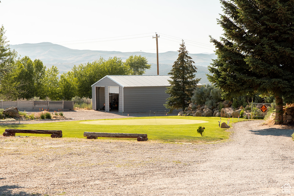 View of yard with a mountain view, an outbuilding, a pole building, and an area to practice putting