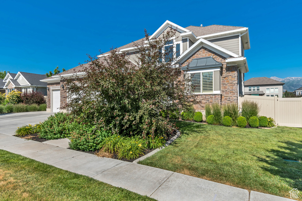 View of front of property featuring stone siding, an attached garage, and concrete driveway