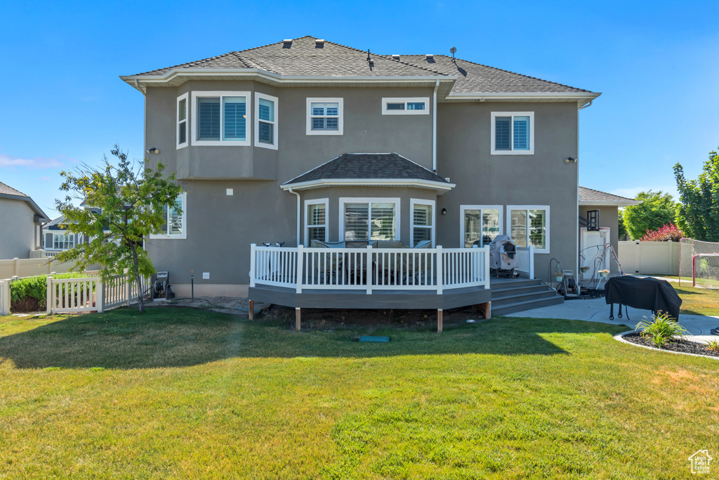 Back of property with a fenced backyard, stucco siding, a deck, and a patio