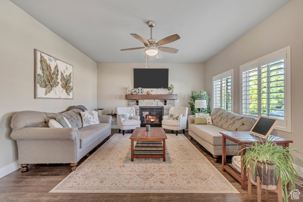 Living room featuring dark wood-style floors, a fireplace, and ceiling fan