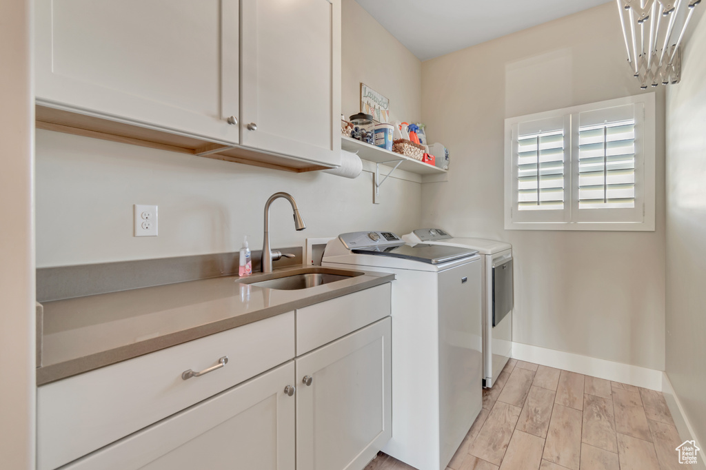 Washroom featuring washer and dryer, cabinet space, and light wood finished floors