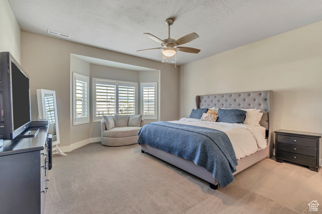 Bedroom with carpet floors, a ceiling fan, and a textured ceiling