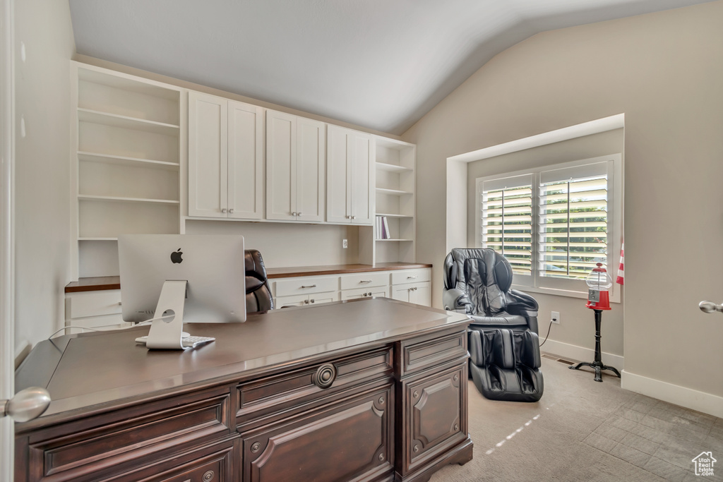 Office area featuring vaulted ceiling, light carpet, and built in study area