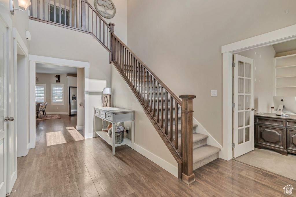 Staircase featuring wood finished floors and a high ceiling