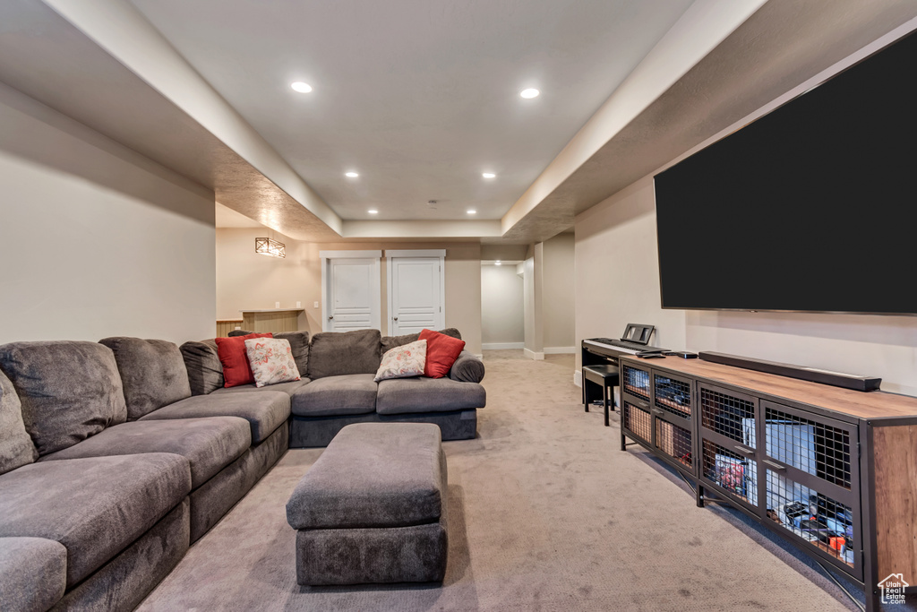 Carpeted living area with recessed lighting and a raised ceiling