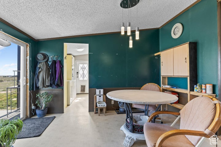 Dining area with a textured ceiling, ornamental molding, and light floors