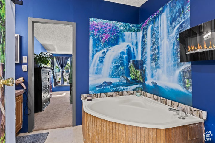 Full bath featuring a garden tub and a textured ceiling