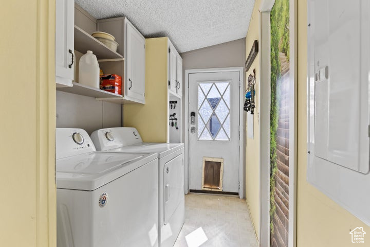 Washroom with washing machine and dryer, cabinet space, and a textured ceiling