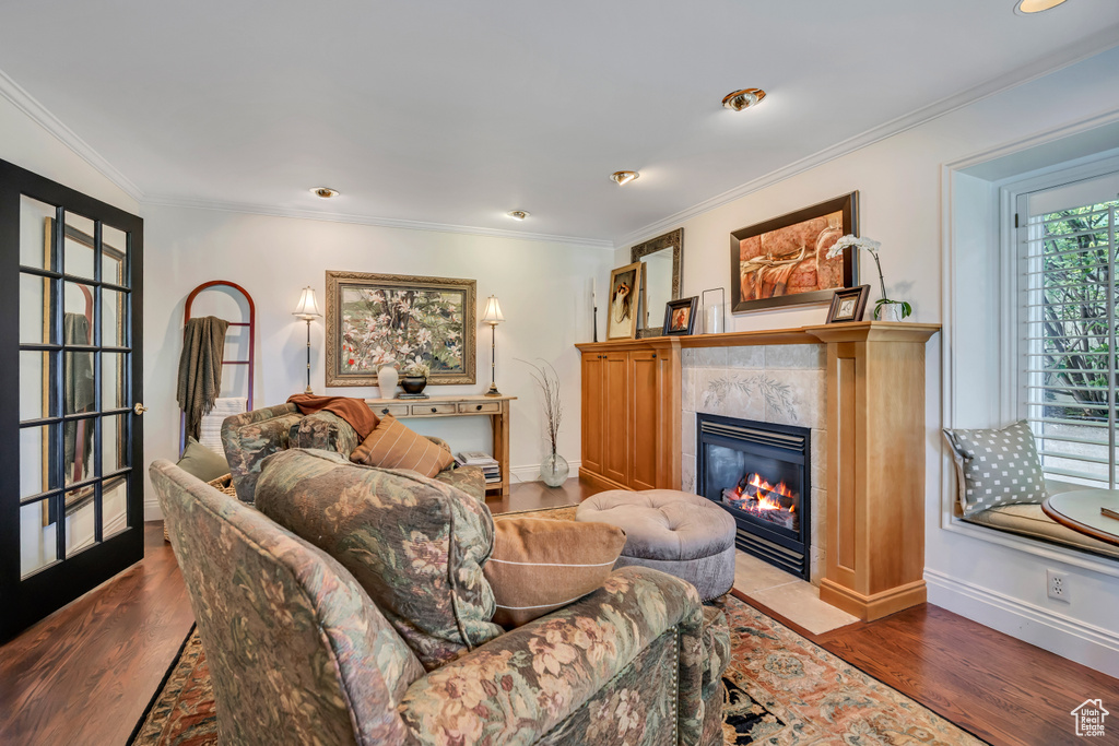 Living room with a fireplace, crown molding, and wood finished floors