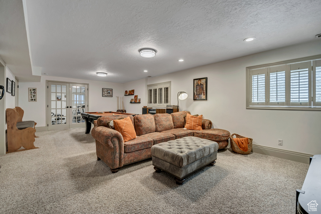 Carpeted living room featuring a textured ceiling, french doors, recessed lighting, pool table, and bar area