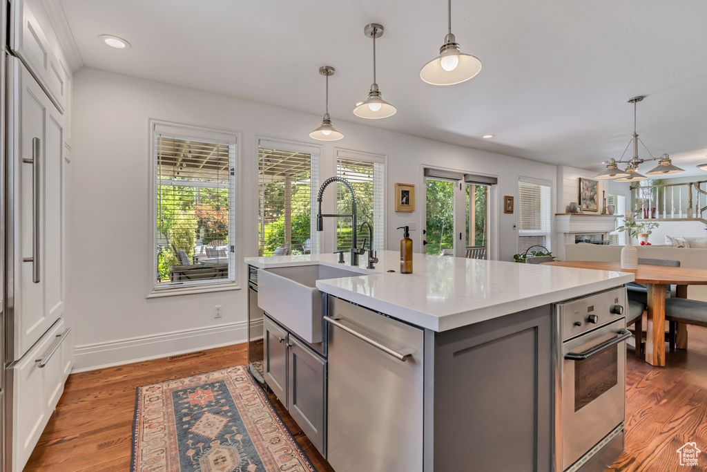 Kitchen with stainless steel appliances, gray cabinets, light countertops, hanging light fixtures, and recessed lighting