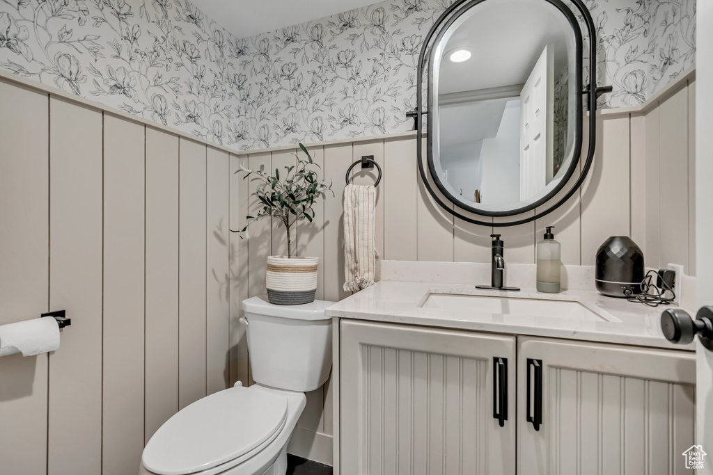 Half bathroom with wallpapered walls and vanity
