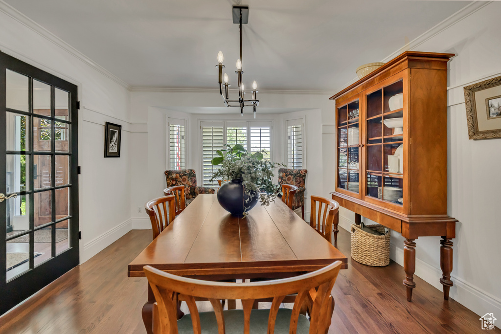 Dining room with wood finished floors, ornamental molding, and a chandelier