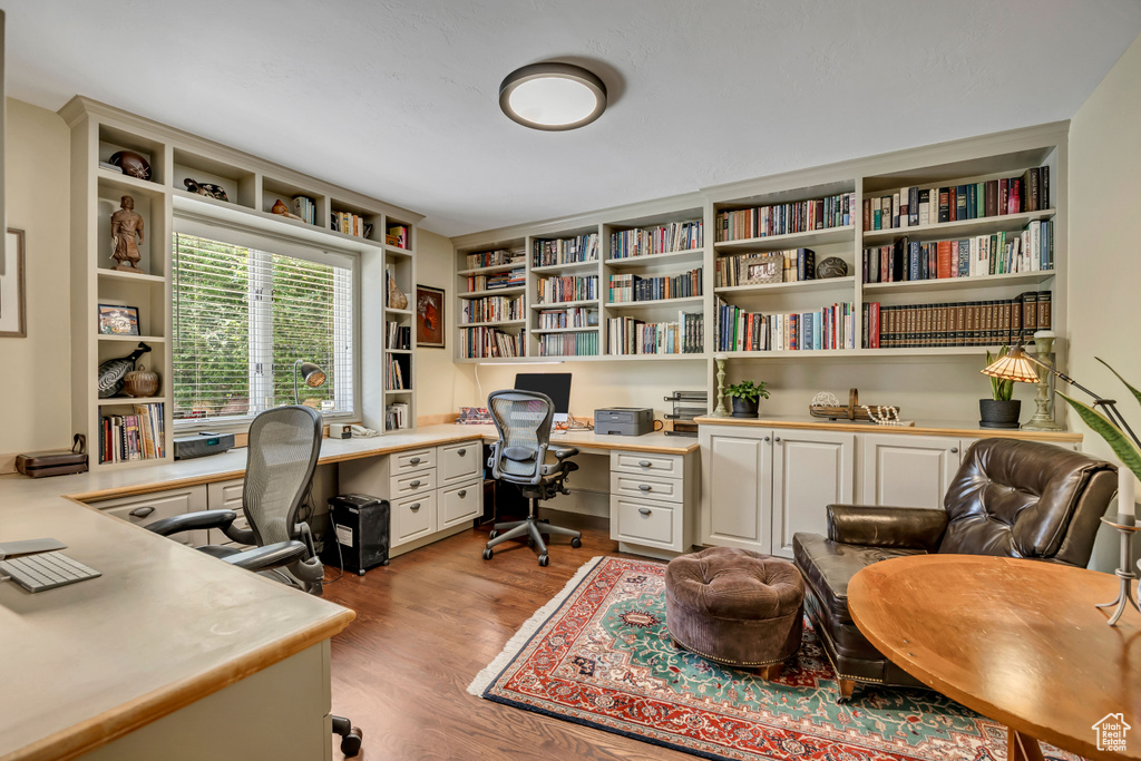 Home office featuring built in study area, light wood finished floors, and built in shelves