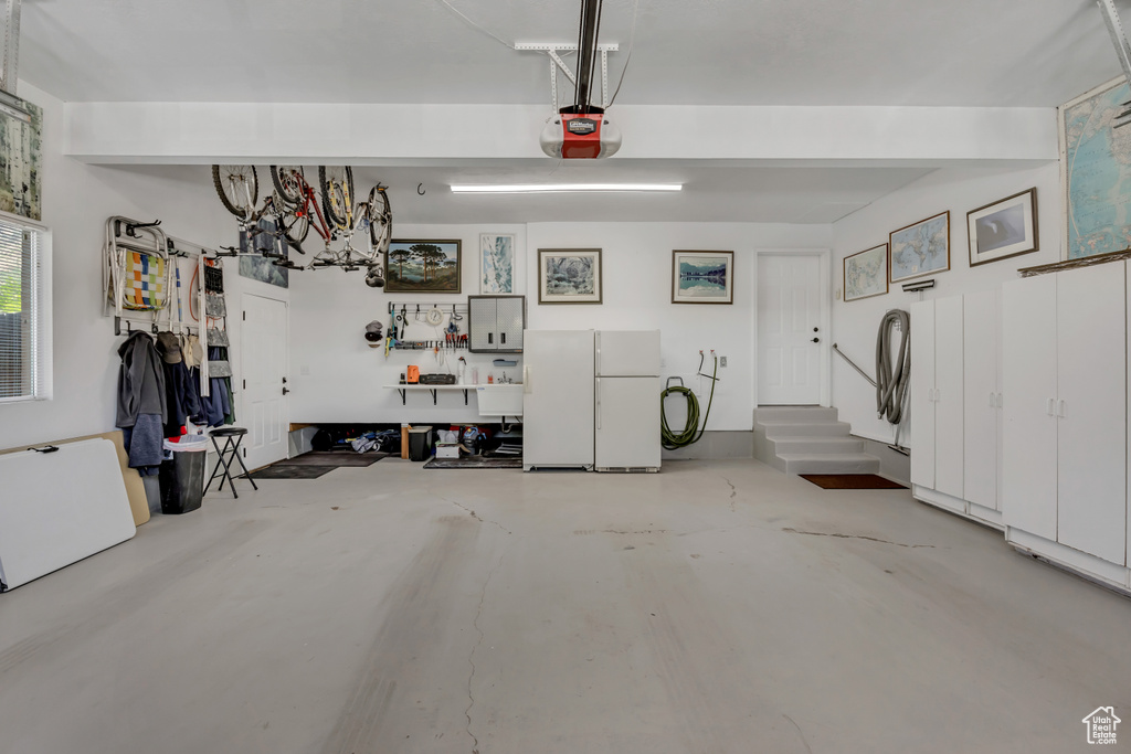 Garage featuring freestanding refrigerator and a garage door opener