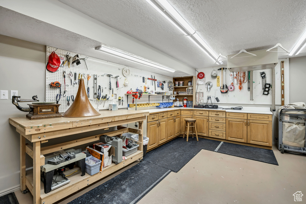 Misc room with a workshop area, a textured ceiling, and concrete floors