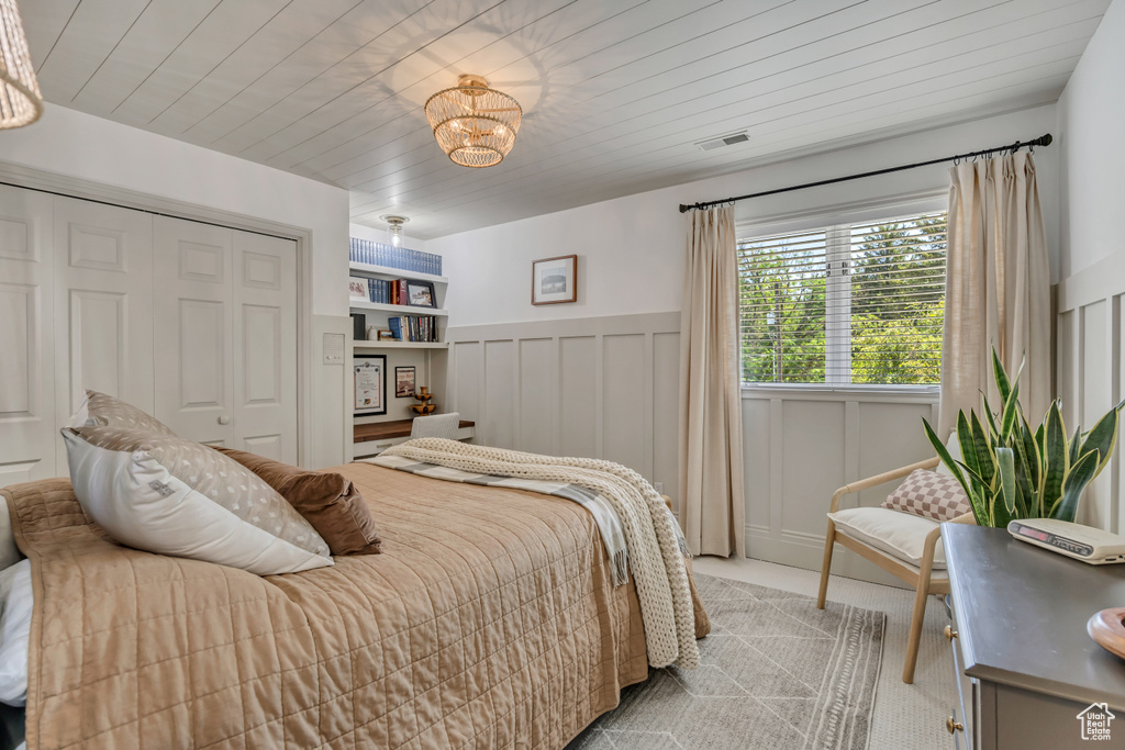 Bedroom featuring a chandelier, wainscoting, a closet, and light colored carpet