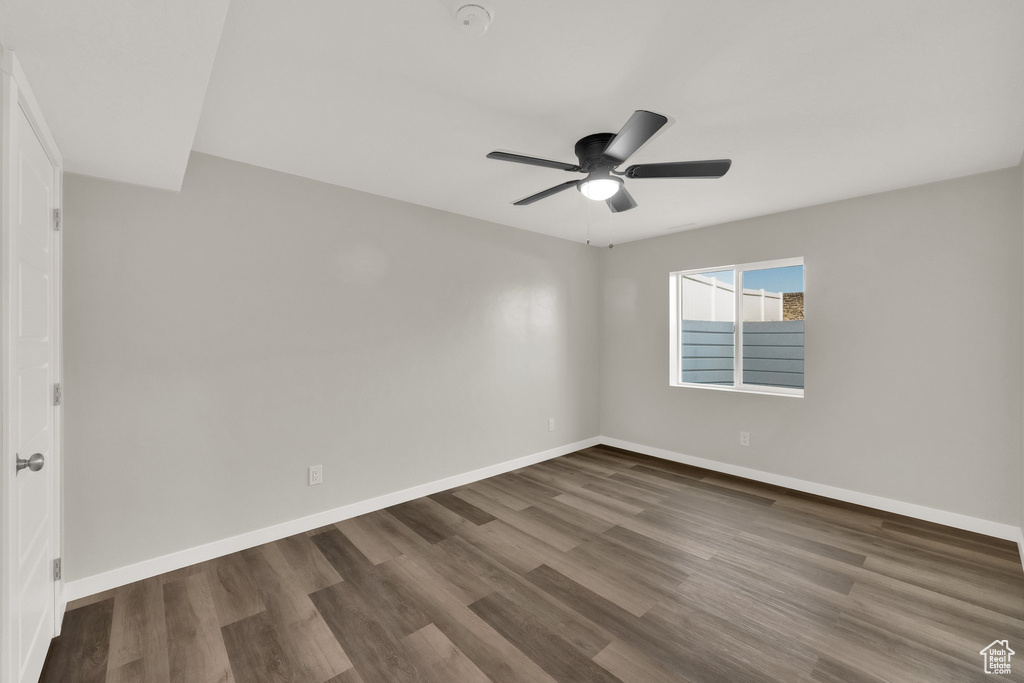 Unfurnished room with dark wood finished floors, a ceiling fan, and a smoke detector