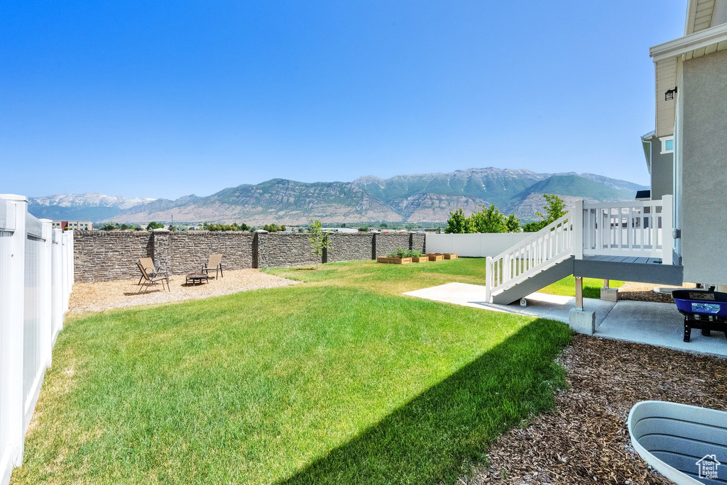 Fenced backyard featuring a mountain view, an outdoor fire pit, and a patio