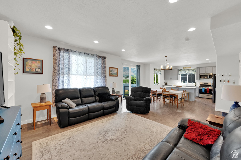Living room featuring a chandelier, light wood finished floors, and recessed lighting