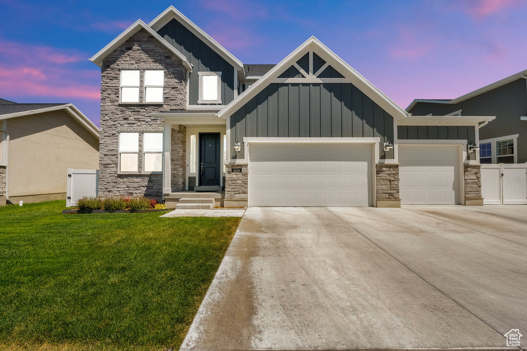 Craftsman-style home featuring board and batten siding, an attached garage, stone siding, and concrete driveway